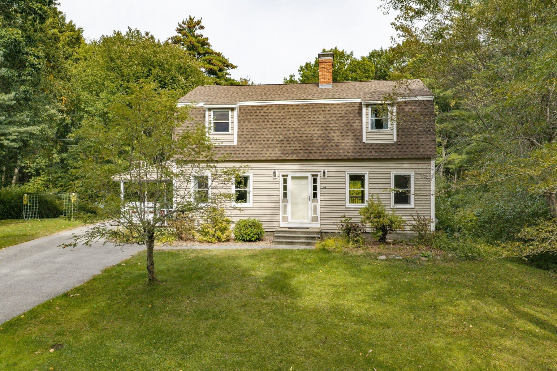 The house from the driveway across the wide front lawn, with a maple in the yard