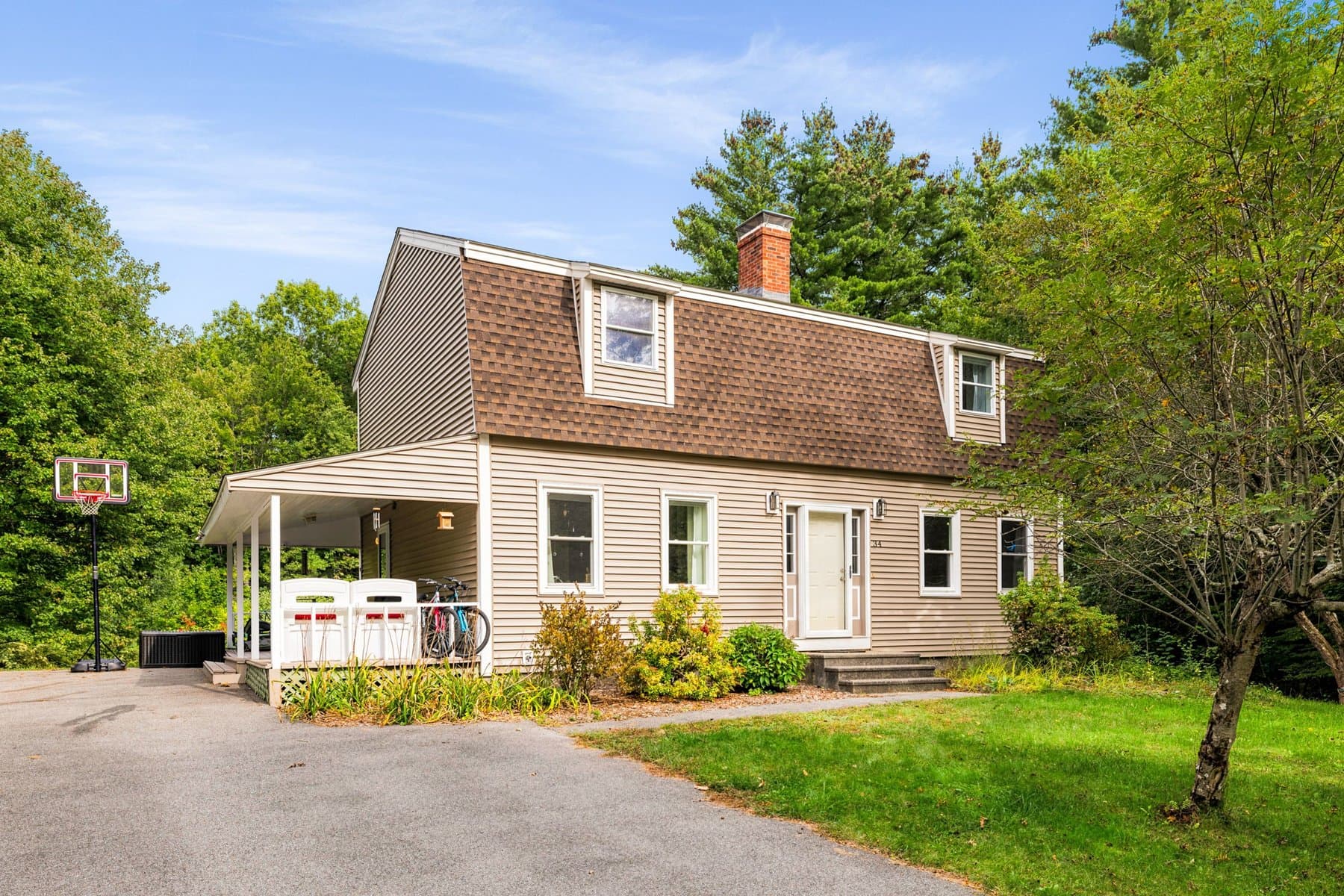 The end of the house from the driveway, with the covered porch and the gambrel roof
