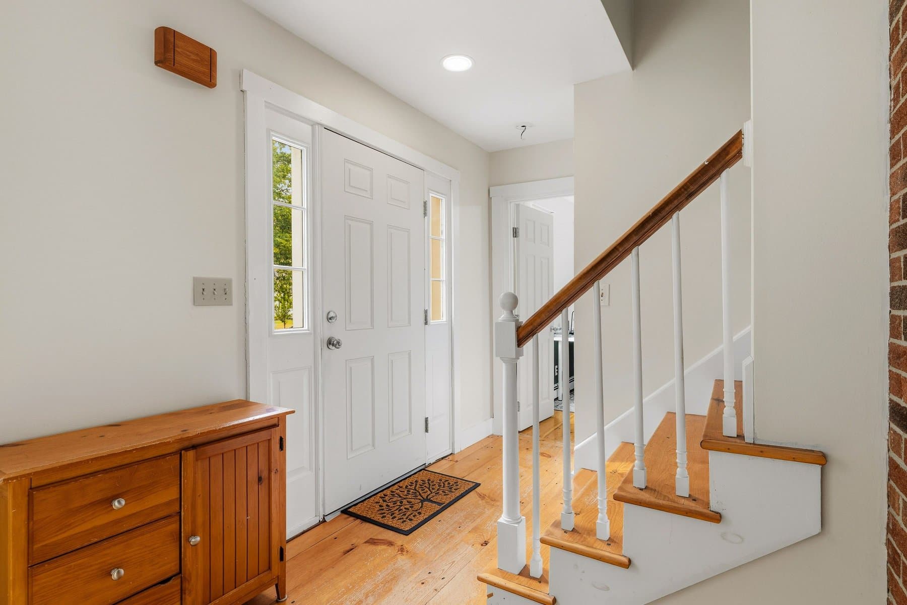 The front entry with the door, the stairs, and the wide pine floor