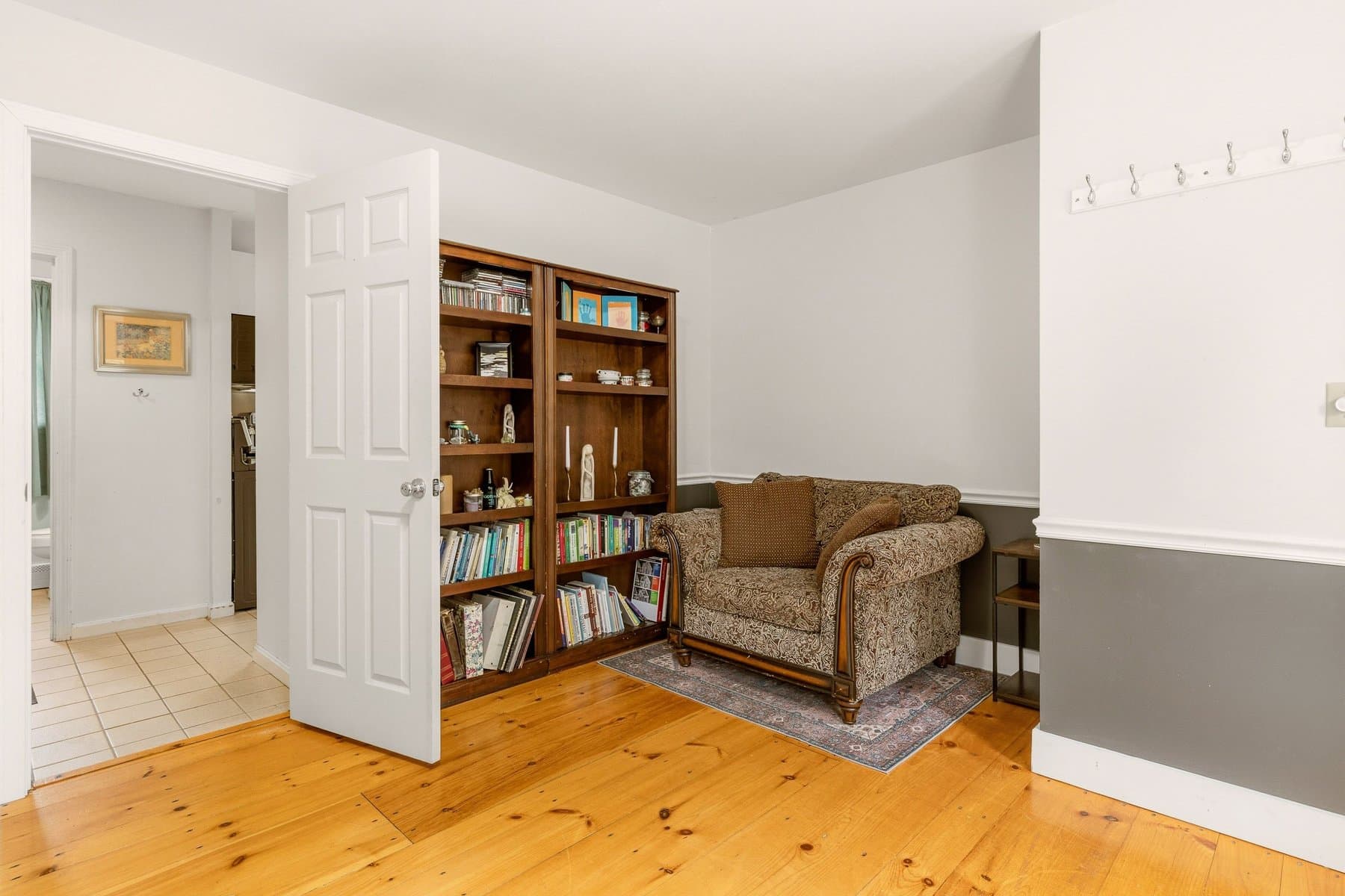 The front room with a built-in bookcase and an armchair, through the door from the hall