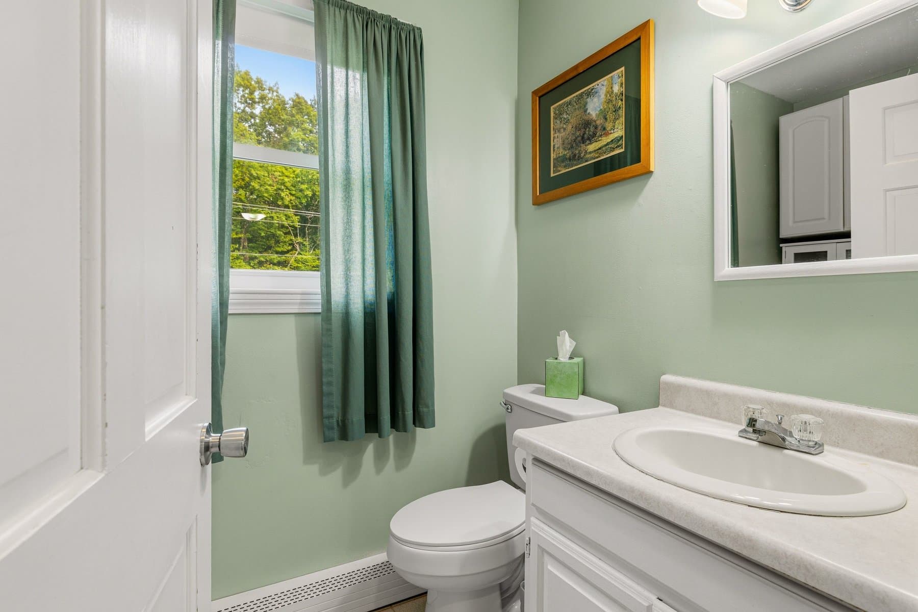 The half bath with a vanity, a window, and green walls