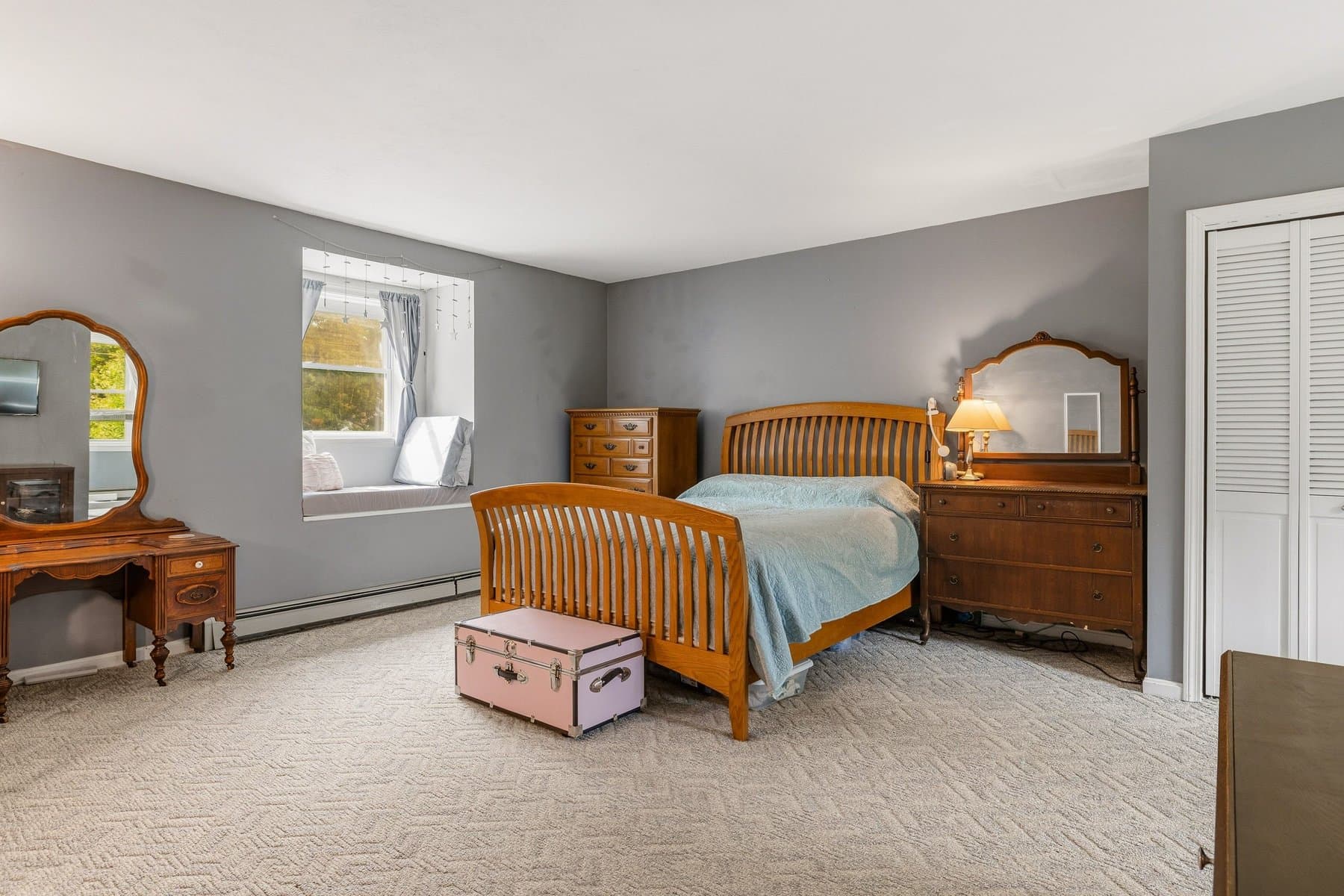 The primary bedroom with a window seat in the dormer, carpet, and a double closet